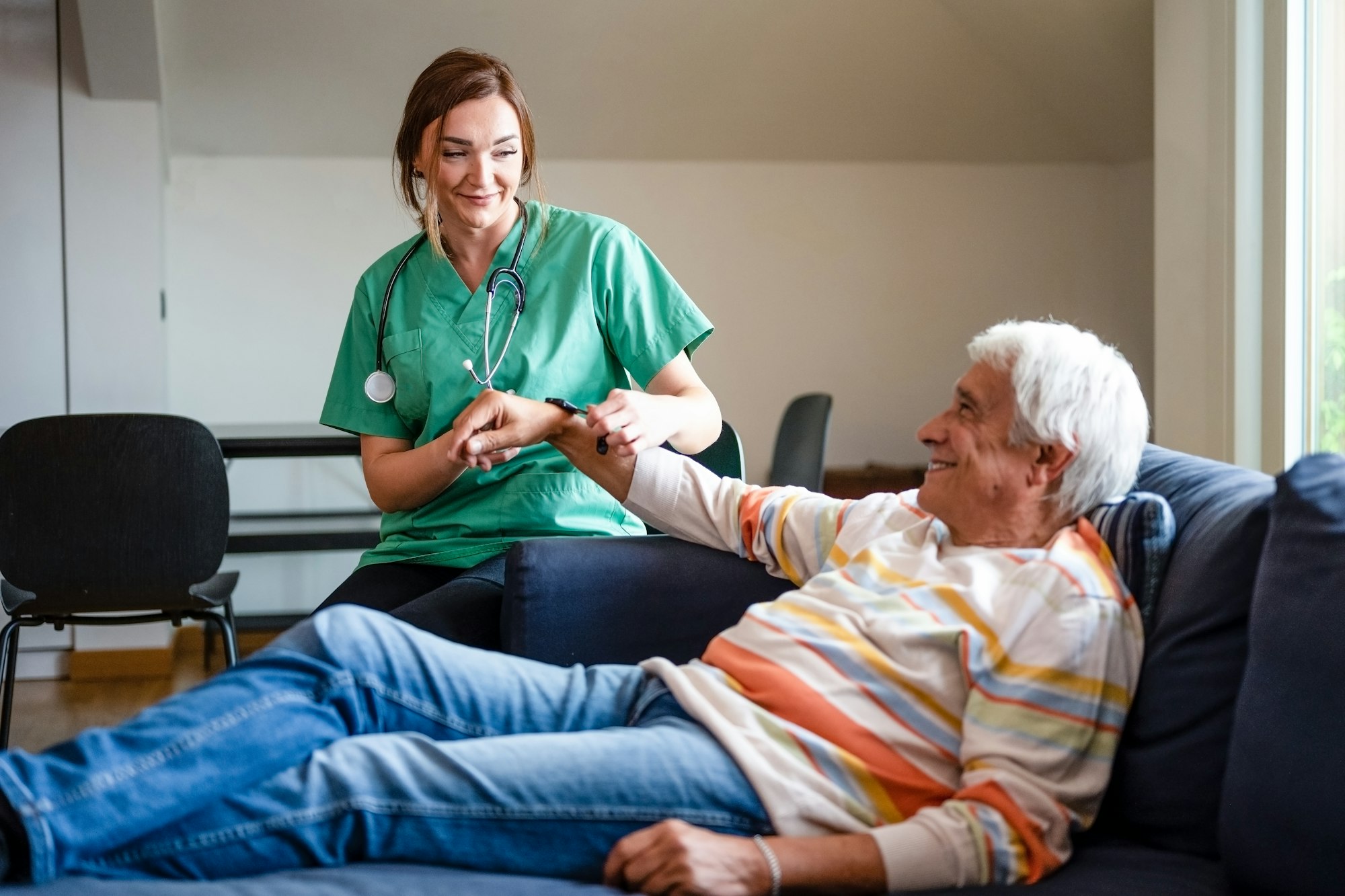 Female doctor of the medical health system putting a smartwatch on a old man