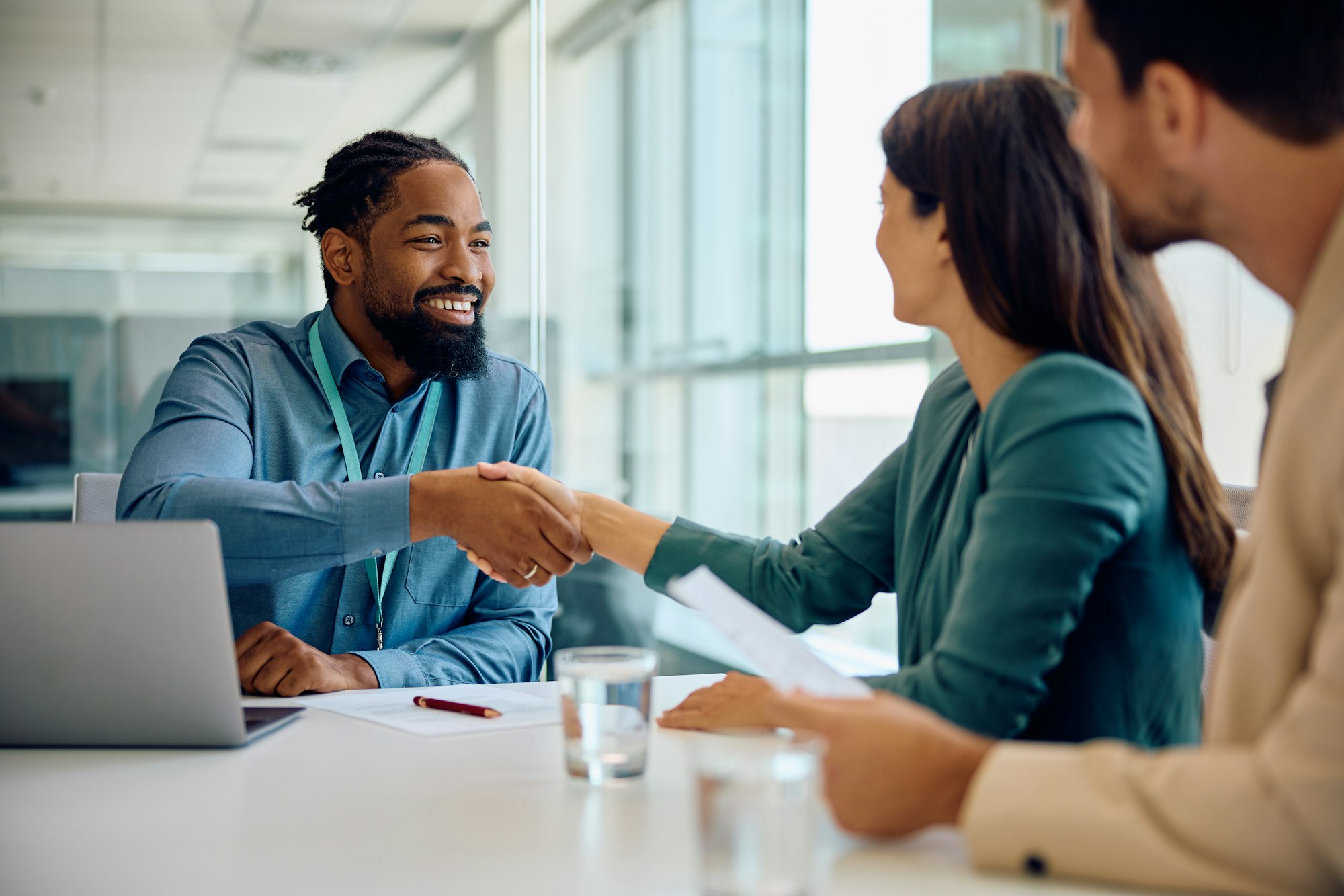 Happy black financial advisor handshaking with his clients during a meeting in the office.