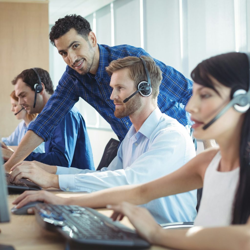 Male supervisor assisting telemarketer at call center